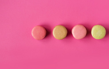 Obraz na płótnie Canvas Colored macaroons on a pink background , colorful almond cookies, pastel colors, vintage card, top view