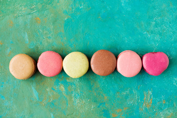 Colored macaroons on a green background , colorful almond cookies, pastel colors, vintage card, top view