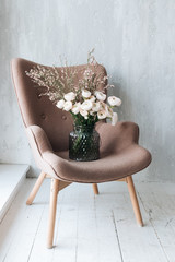 Beautiful spring bouquet of tender pink ranunculus flowers on armchair, elegant floral decoration 