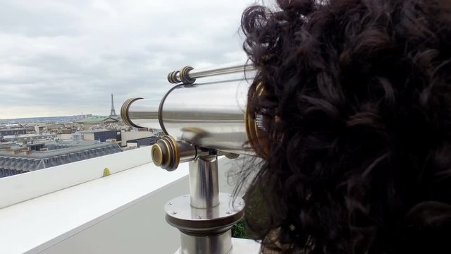 Tourist woman enjoy Paris cityscape view with coin binocular telescope at top terace balcony in Galery Lafayette