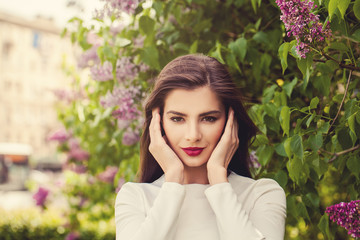 Perfect young woman with makeup on floral background outdoors