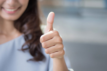 successful girl pointing thumb up; portrait of cheerful smiling woman pointing up approving, yes,...