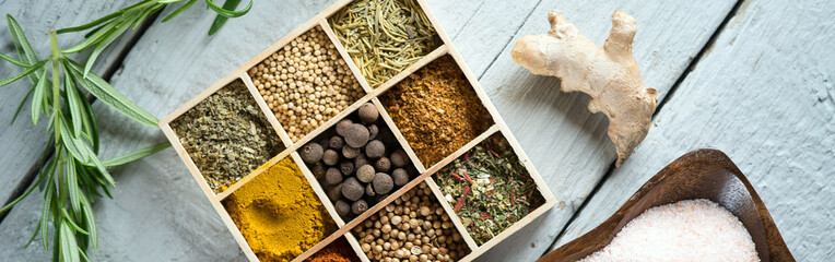 colorful fresh herbs and spices assortment on a white wooden background