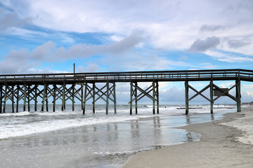 Cloudy evening at Atlantic ocean beach. Atlantic ocean waves, scenic view with the wooden pier at Pawleys Island, South Carolina, Myrtle Beach area, USA.