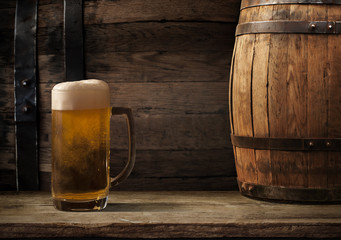 Oktoberfest beer barrel and beer glasses with wheat and hops on wooden table