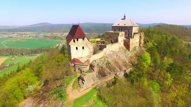 Drone flight around Tocnik Castle in blooming orchard. A royal chateau of Wenceslas IV from the 14th century, adjusted in the Renaissance and the Baroque styles. Famous Czech monument from above. 