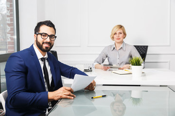 Business colleagues dressed in suits, boss and worker in white office interior