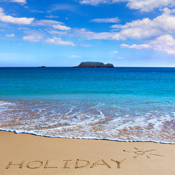 HOLIDAY insctiption under the sun drawing on wet beach sand with the turquoisesea and the island on background