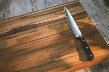Cutting board and a kitchen knife on wooden background selected focus