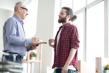 Obraz premium Two colleagues standing and communicating with each other at office