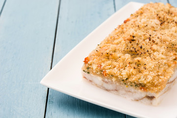 White fish casserole with cheese on blue wooden background. Copyspace