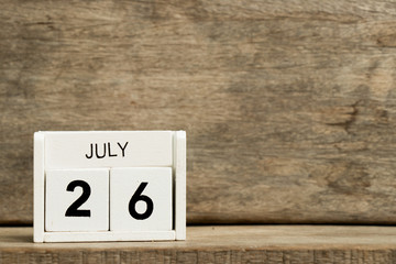 White block calendar present date 26 and month July on wood background