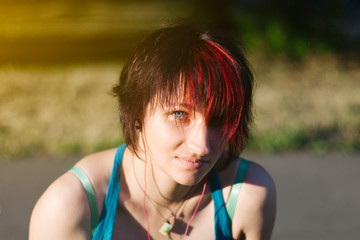Portrait of young skateboarder girl resting in park, outdoors. Red hair.