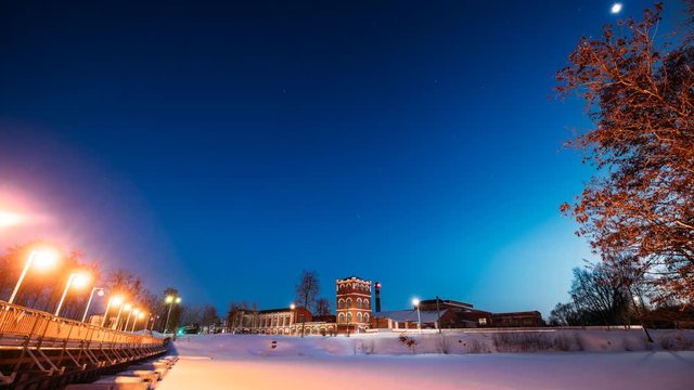 Dobrush, Gomel Region, Belarus. Time Lapse Time-lapse Timelapse From Evening To Night Of Old Paper Factory Tower In Winter Season. Night Stars Sky Above Historical Heritage And Landmark