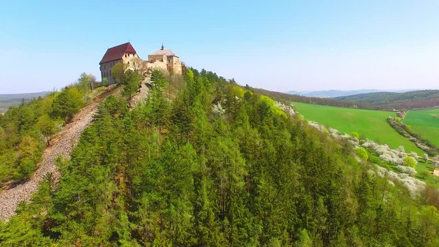 Drone flight around Tocnik Castle in blooming orchard. A royal chateau of Wenceslas IV from the 14th century, adjusted in the Renaissance and the Baroque styles. Famous Czech monument from above. 
