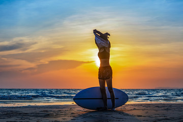surfboard woman takes off sport shirt to practice water sport exercise at the sea