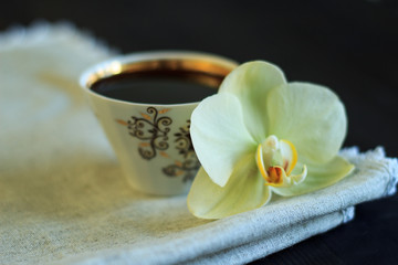 Black coffee and orchid flower. Close-up.