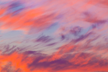 Beautiful cloudscape at scarlet sunset with colorful contrasting cirrus clouds
