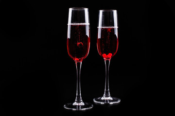 Glass with berries and red champagne alcohol cocktail stands on black background