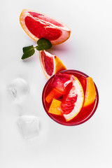 Cocktail of vodka, grenadine, pomegranate, ice and mint stands on a white table