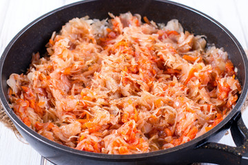 The process of cooking stewed cabbage with carrots and spices in a frying pan