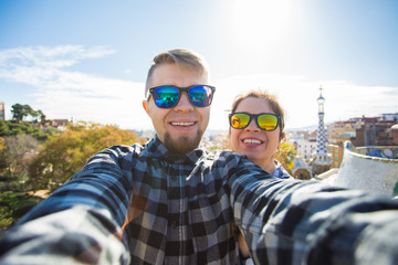 Travel couple happy talking selfie portrait with smartphone in Park Guell, Barcelona, Spain. Beautiful young couple looking at camera taking photo with smart phone smiling in love