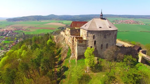 Drone flight around Tocnik Castle in blooming orchard. A royal chateau of Wenceslas IV from the 14th century, adjusted in the Renaissance and the Baroque styles. Famous Czech monument from above. 