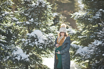 Portrait of a girl in a position for a walk among the snow covered fir trees