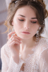 Portrait of beautiful bride. Morning of the bride. Wedding morning. Makeup. Bride with cones and fair hair. Fragile bride in white lace negligee