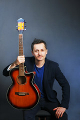 Portrait of young hipster moustached musician man in casual jacket with guitar. Practicing in playing guitar concept. Handsome young men playing acoustic guitar song.