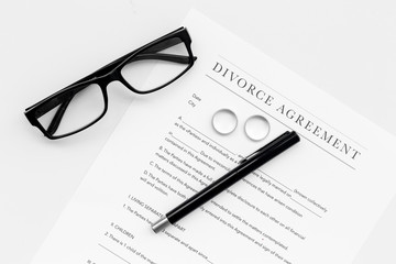 Divorce agreement. Wedding ring on document on white background top view
