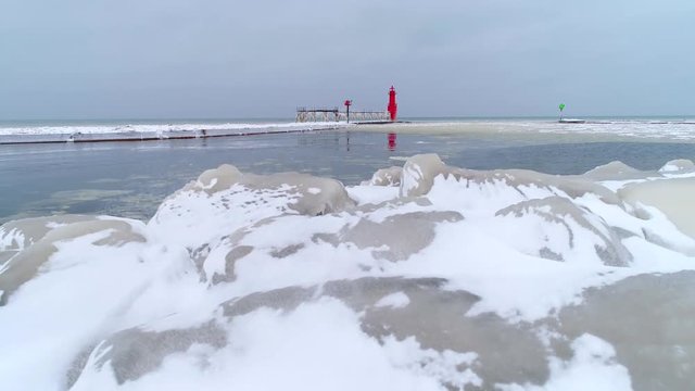 Scenic lighthouse with icicles on pier catwalk after storm, aerial view.
