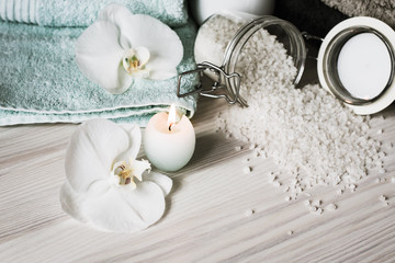 Spa treatments, spa items. Towels, sea salt and a candle on a wooden background.