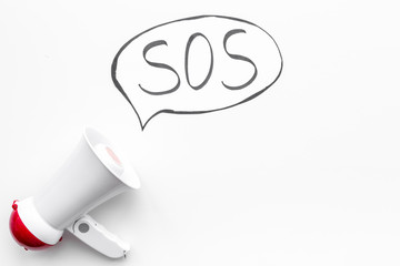 Ask for help concept. Megaphone near cloud with word SOS on white background top view copy space