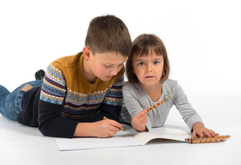 Children lie on the floor and draw with pencils.  On isolated white background.