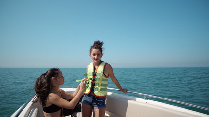 Obraz premium Two beautiful teen girls dancing on a yacht cruising fast on open sea horizon, SLOW MOTION