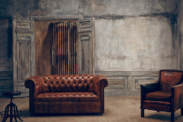 Leather sofa, stool and armchair in empty room