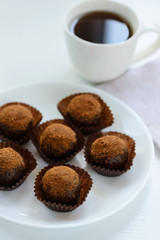 Chocolate petit fours on a white table with a cup of coffee