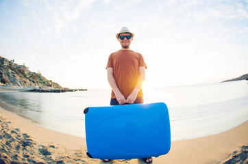 Fototapeta premium Man holding suitcase against the sea the sea. Travel concept.