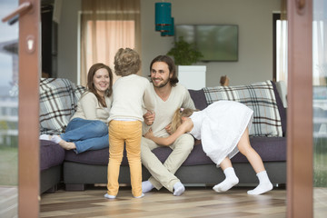 Happy cheerful family playing at home on weekend, active kids having fun with parents relaxing on sofa in cozy living room, smiling mom and dad enjoying spending time with children son and daughter