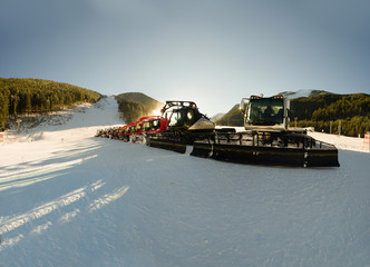 Naklejka premium Snowcat, Ratrac, Tractor, Red Group of Snow-grooming machine on snow hill ready for skiing slope preparations, Bansko, Bulgaria