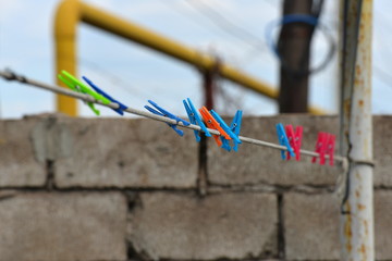 Multicolored plastic clothespins hang on the clothesline of the house.