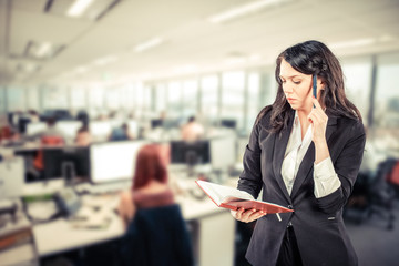 young business woman holding notepad and talking on mobile phone