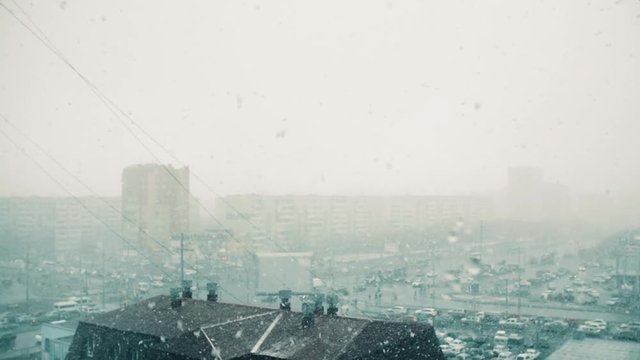 Bad weather in modern city and heavy snowfall view from window