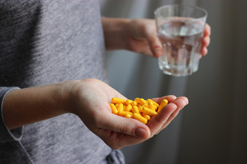 Obraz premium a handful of pills and a glass of water in female hands. Concept of health.