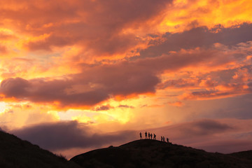 Silhouetted climbers on volcanic rim of Masaya volcano at sunset