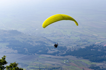 Paraglide silhouette flying over misty mountain valley