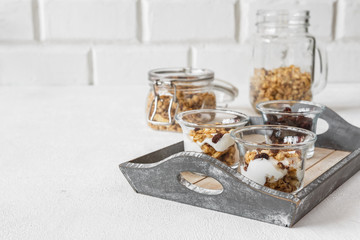 Grnola, raisins, milk in glass jars and various ingredients for a super meal with copy space on a light background