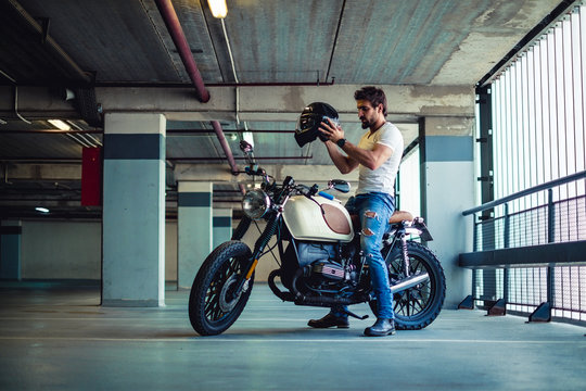 Man putting on motorcycle helmet in a garage