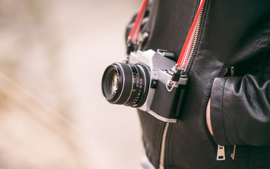 Old vintage camera on a halter neklice leather coat